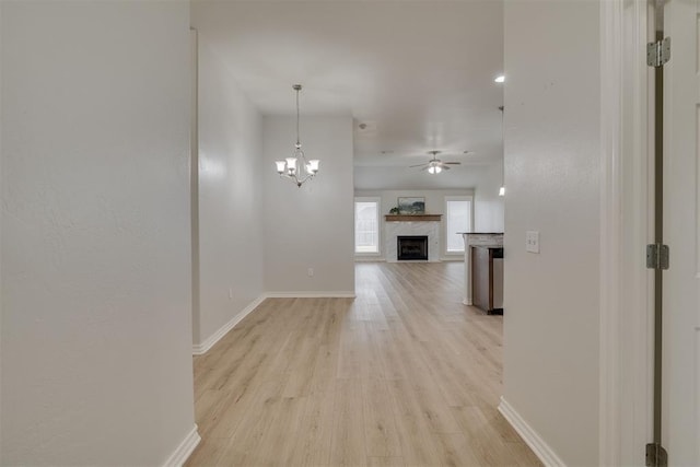 hallway featuring an inviting chandelier, light wood-style flooring, and baseboards