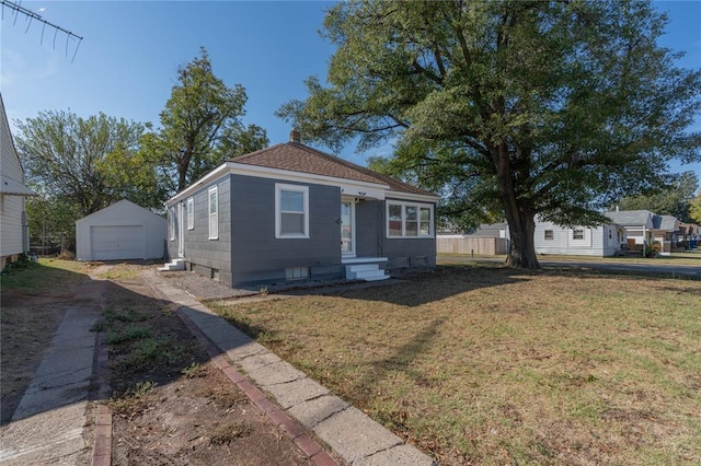 bungalow-style home featuring a garage, an outdoor structure, and a front lawn