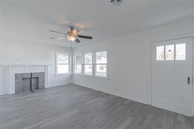 unfurnished living room featuring a tiled fireplace, hardwood / wood-style floors, and ceiling fan