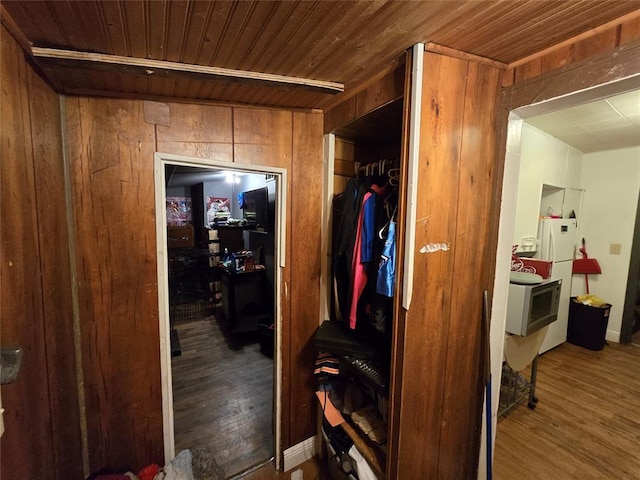 hallway with dark wood-type flooring, wooden ceiling, and wooden walls