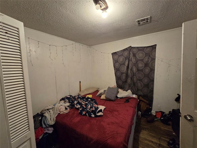 bedroom with dark wood-type flooring, a closet, and a textured ceiling