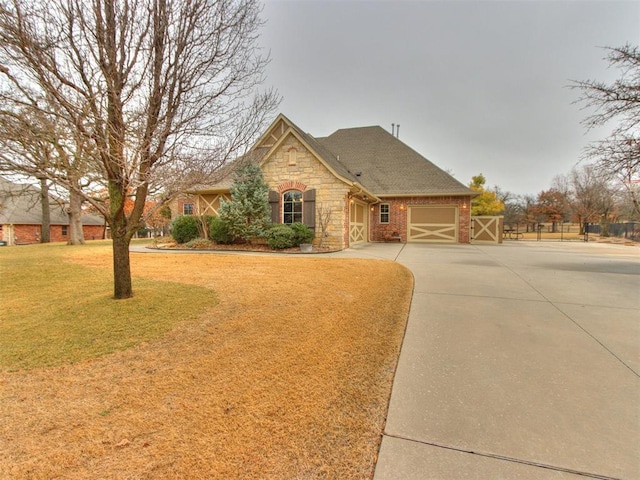 view of front facade featuring brick siding, an attached garage, a front yard, stone siding, and driveway