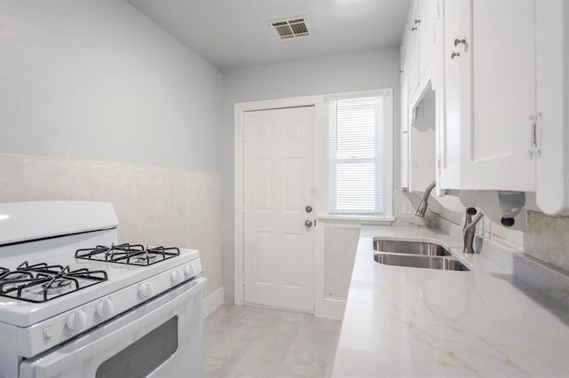 kitchen with white cabinetry, sink, and white gas stove