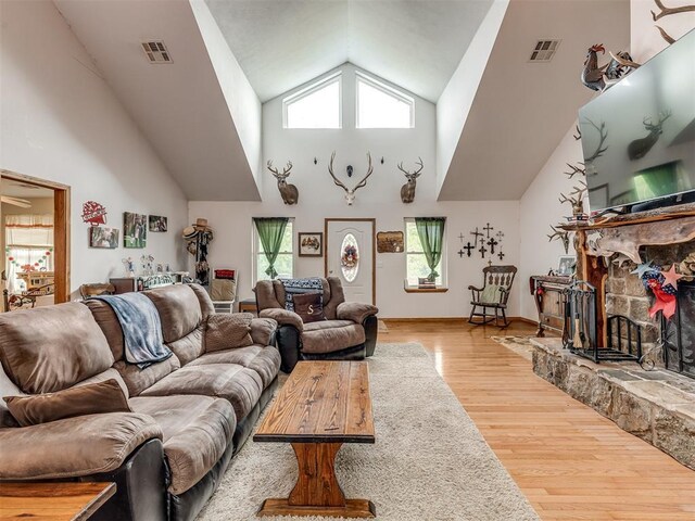 living room featuring a fireplace, high vaulted ceiling, and light hardwood / wood-style flooring