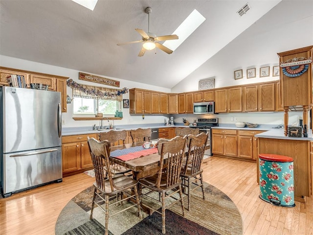 kitchen featuring light hardwood / wood-style flooring, ceiling fan, a skylight, stainless steel appliances, and a center island