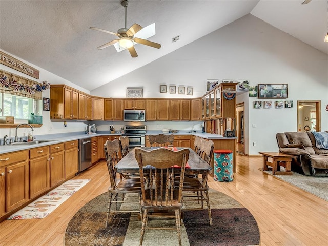 kitchen with high vaulted ceiling, sink, ceiling fan, light hardwood / wood-style floors, and stainless steel appliances