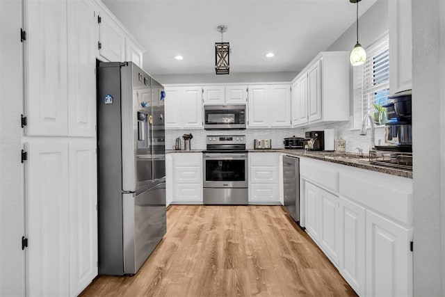 kitchen featuring white cabinetry, appliances with stainless steel finishes, decorative light fixtures, and decorative backsplash