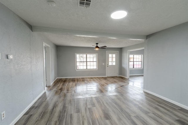 empty room featuring ceiling fan, plenty of natural light, hardwood / wood-style floors, and a textured ceiling