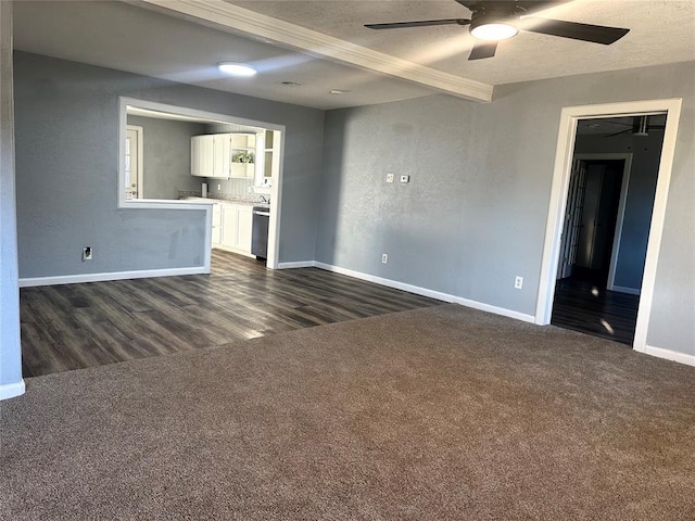 unfurnished living room with a ceiling fan, baseboards, dark colored carpet, and beam ceiling