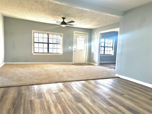 empty room with a ceiling fan, baseboards, a textured ceiling, and wood finished floors