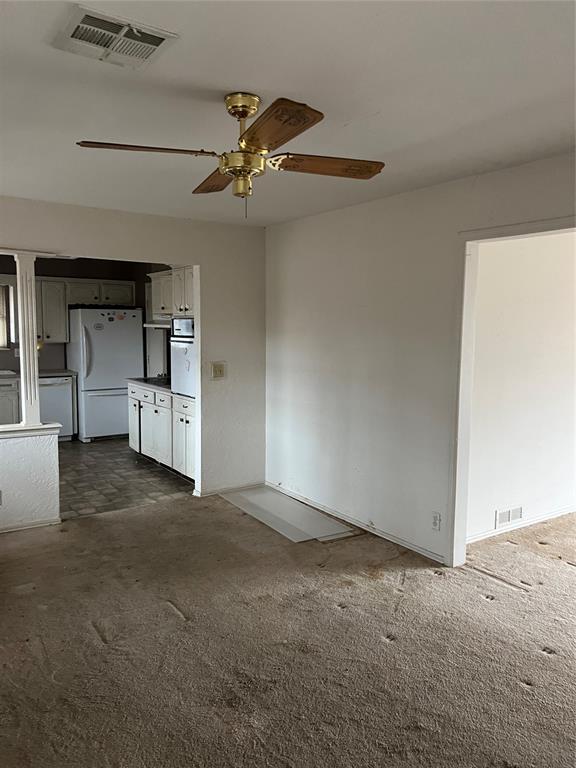 unfurnished living room featuring ceiling fan and dark carpet