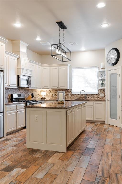 kitchen with pendant lighting, white cabinetry, appliances with stainless steel finishes, and a kitchen island