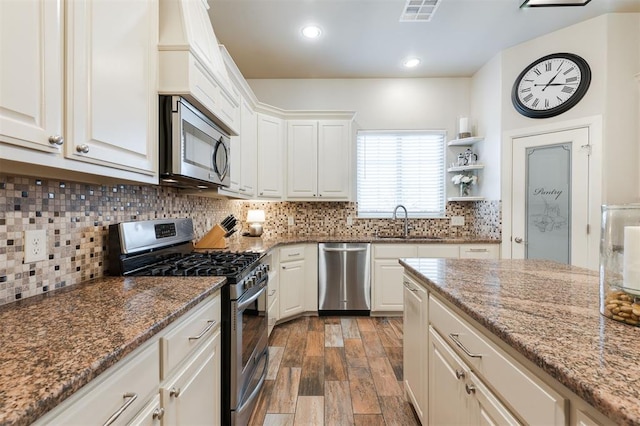 kitchen with sink, white cabinetry, stone countertops, dark hardwood / wood-style floors, and stainless steel appliances