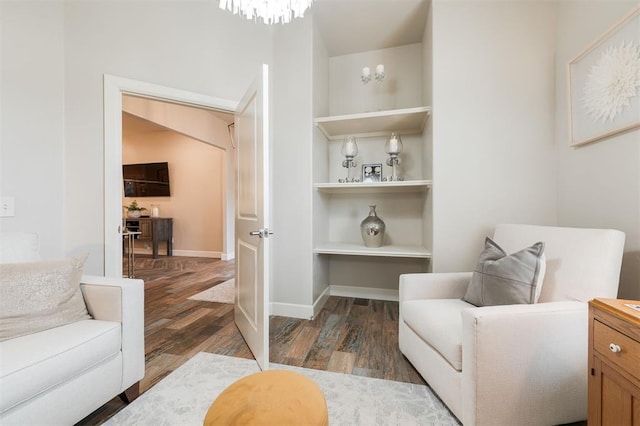 sitting room featuring a chandelier, built in features, and dark hardwood / wood-style flooring