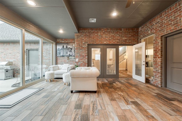 interior space with wood-type flooring, brick wall, and french doors