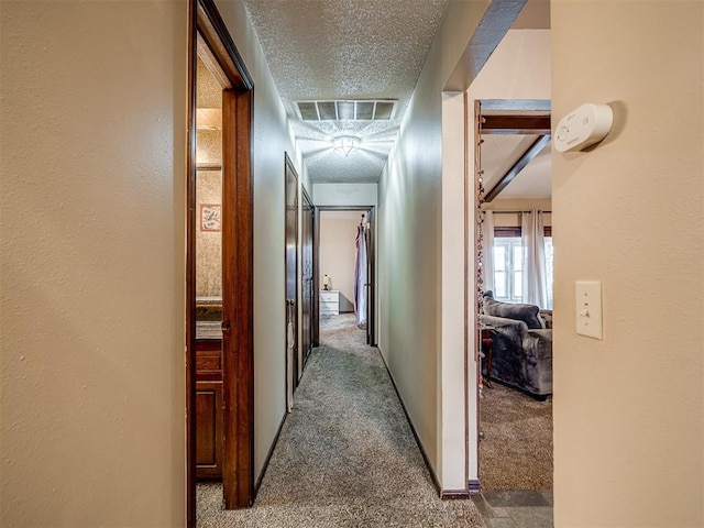 hallway with carpet flooring and a textured ceiling