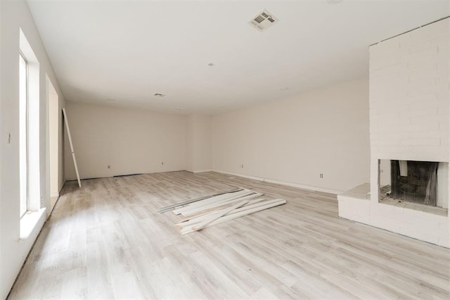 unfurnished living room featuring a fireplace and light hardwood / wood-style flooring