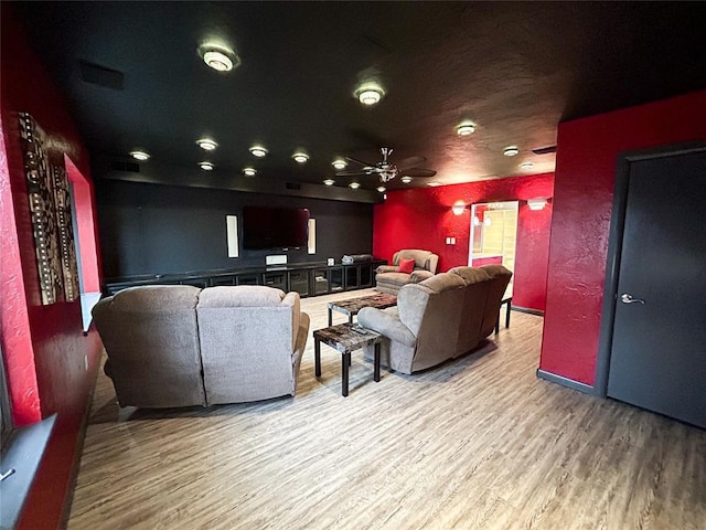 home theater room featuring hardwood / wood-style floors and ceiling fan