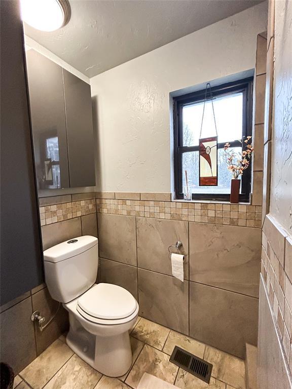 bathroom with tile walls and toilet