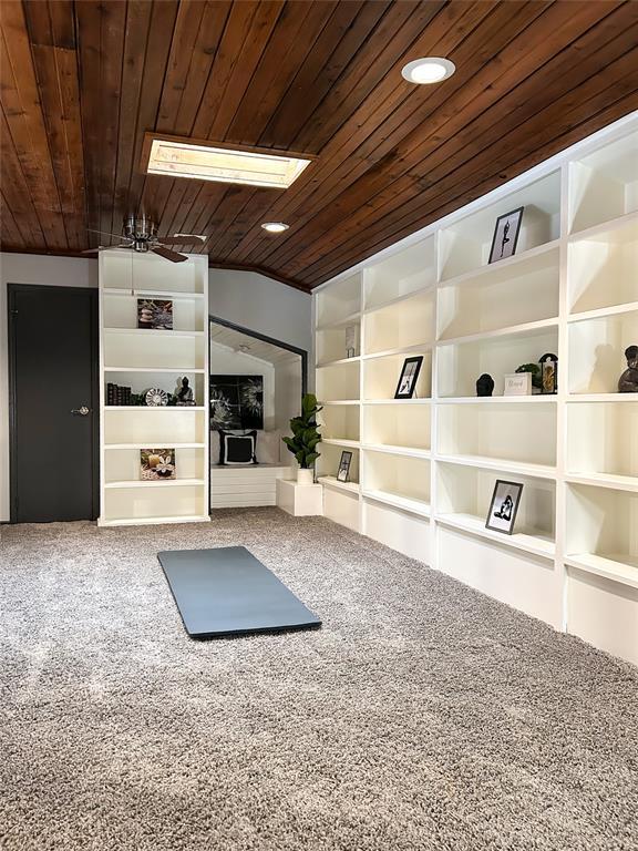 workout area featuring vaulted ceiling, carpet flooring, wooden ceiling, and built in features