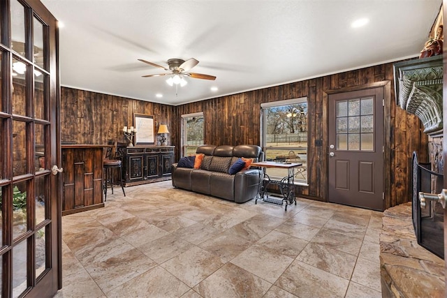 living room featuring ceiling fan and wooden walls