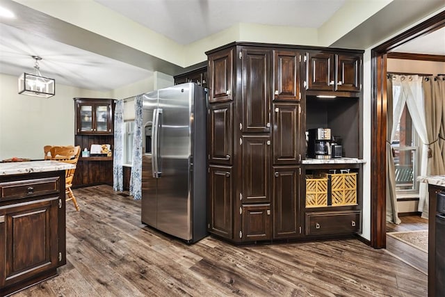 kitchen with pendant lighting, wood-type flooring, stainless steel fridge with ice dispenser, and dark brown cabinets