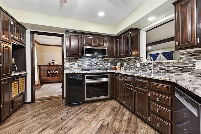 kitchen with dark brown cabinetry, sink, light wood-type flooring, appliances with stainless steel finishes, and light stone countertops