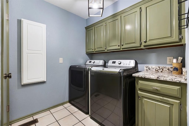 laundry area featuring cabinets, light tile patterned floors, and washing machine and clothes dryer