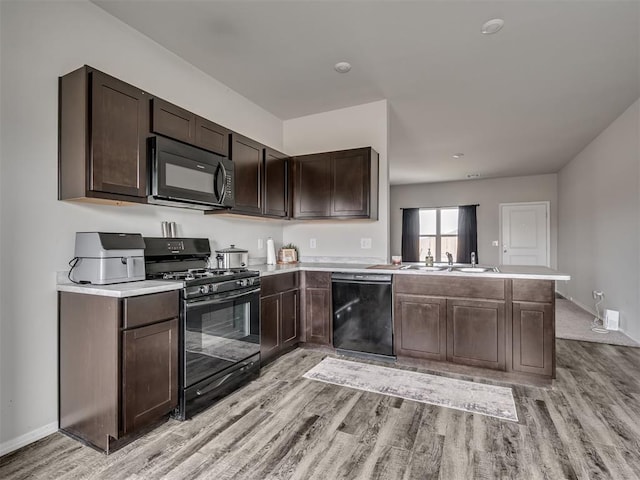 kitchen featuring sink, light hardwood / wood-style flooring, dark brown cabinets, black appliances, and kitchen peninsula