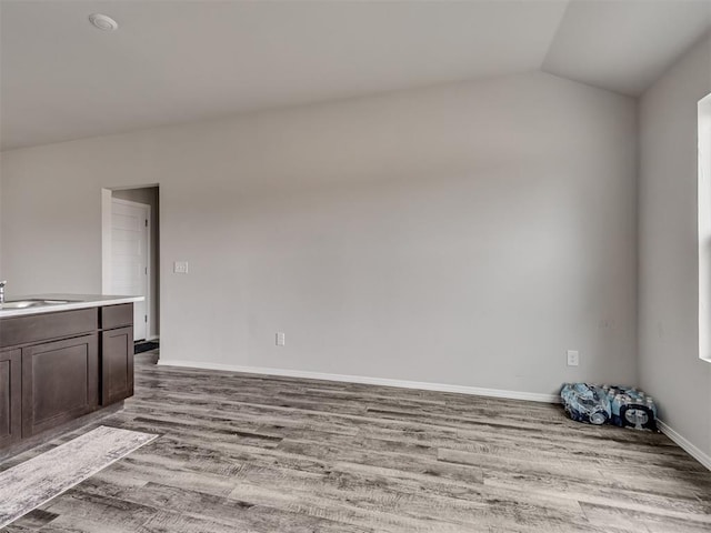 unfurnished room featuring lofted ceiling, sink, and light wood-type flooring