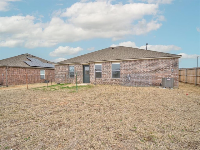back of property with central AC and a lawn