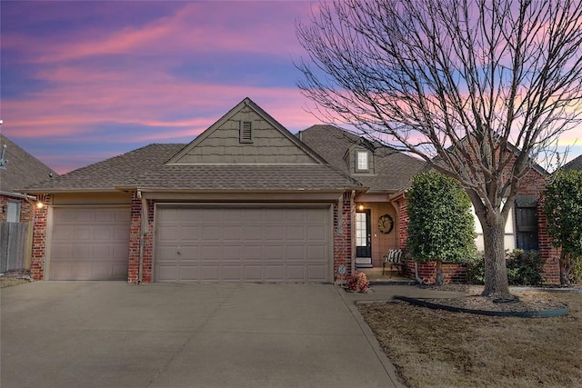 view of front of property with an attached garage, driveway, roof with shingles, and brick siding