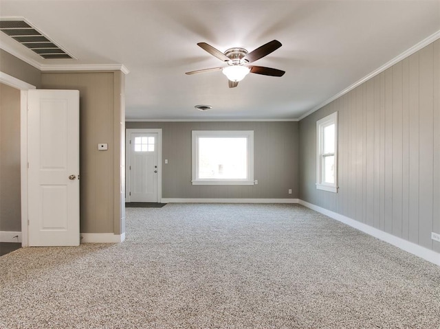 carpeted spare room featuring plenty of natural light, ornamental molding, and ceiling fan