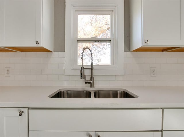 kitchen with tasteful backsplash, white cabinetry, and sink