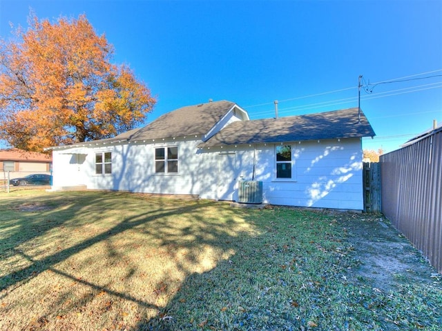 rear view of house featuring central AC unit and a lawn