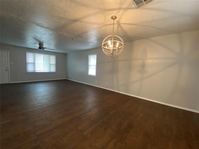 empty room with dark hardwood / wood-style floors, ceiling fan with notable chandelier, and a textured ceiling