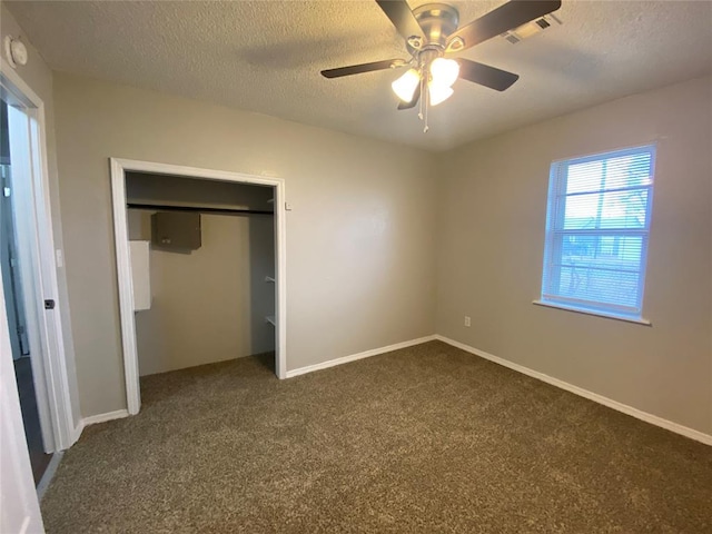 unfurnished bedroom featuring ceiling fan, a closet, a textured ceiling, and dark colored carpet