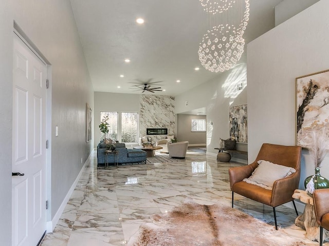 living room featuring a premium fireplace and ceiling fan with notable chandelier