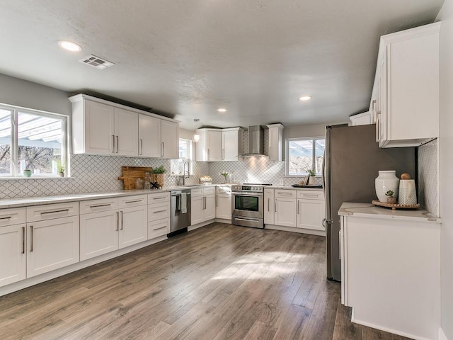 kitchen featuring wall chimney exhaust hood, sink, dark hardwood / wood-style floors, stainless steel appliances, and white cabinets