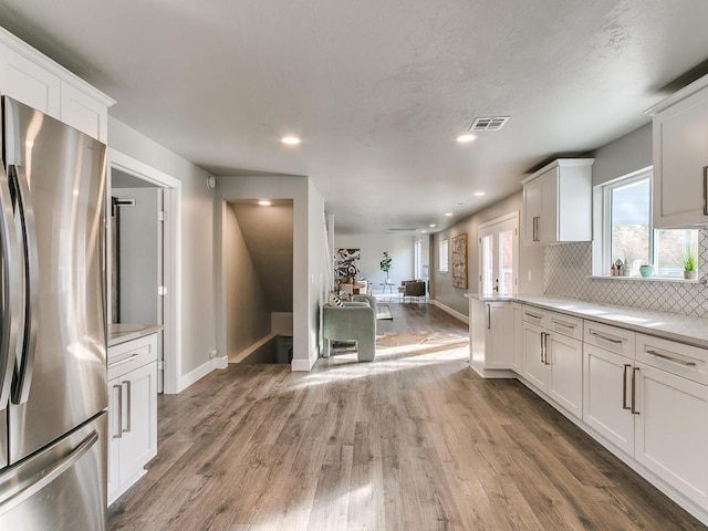 kitchen featuring white cabinetry, backsplash, dark wood-type flooring, and stainless steel refrigerator