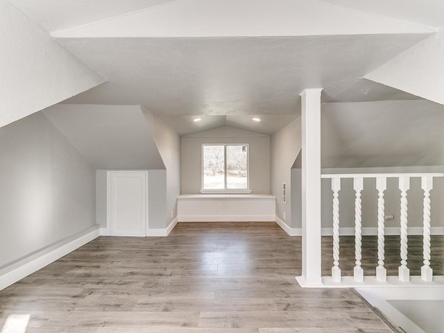 additional living space featuring vaulted ceiling and wood-type flooring