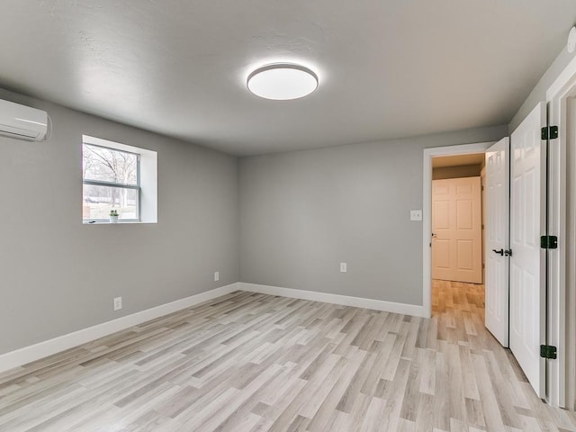 empty room featuring light hardwood / wood-style floors and an AC wall unit