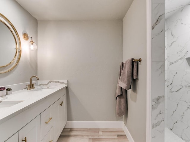 bathroom featuring hardwood / wood-style flooring, vanity, and a tile shower