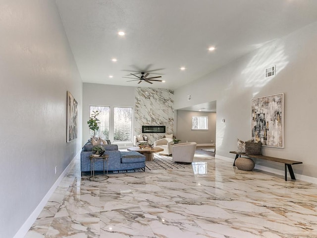 living room with a towering ceiling, a fireplace, and ceiling fan