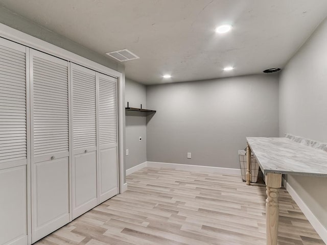 clothes washing area with light hardwood / wood-style flooring