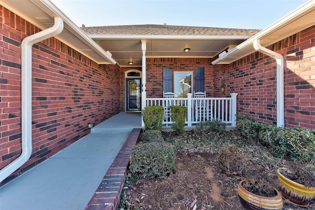 property entrance featuring a porch and brick siding