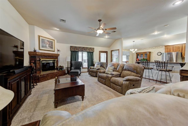 living room with visible vents, light colored carpet, vaulted ceiling, a fireplace, and ceiling fan with notable chandelier