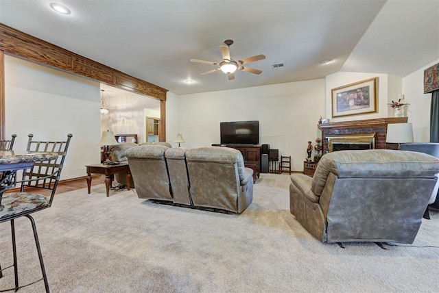 living area featuring a ceiling fan, a brick fireplace, visible vents, and light carpet