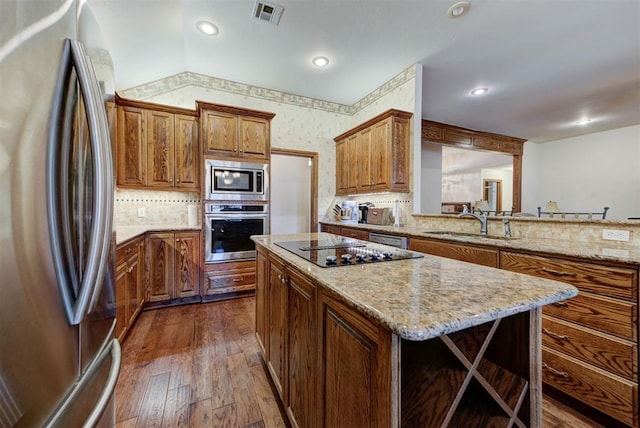 kitchen with a center island, dark wood-style flooring, brown cabinets, visible vents, and appliances with stainless steel finishes