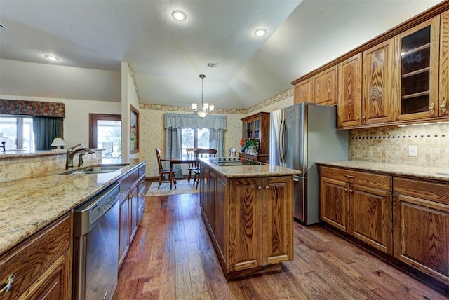 kitchen featuring lofted ceiling, brown cabinets, a center island, stainless steel appliances, and a sink